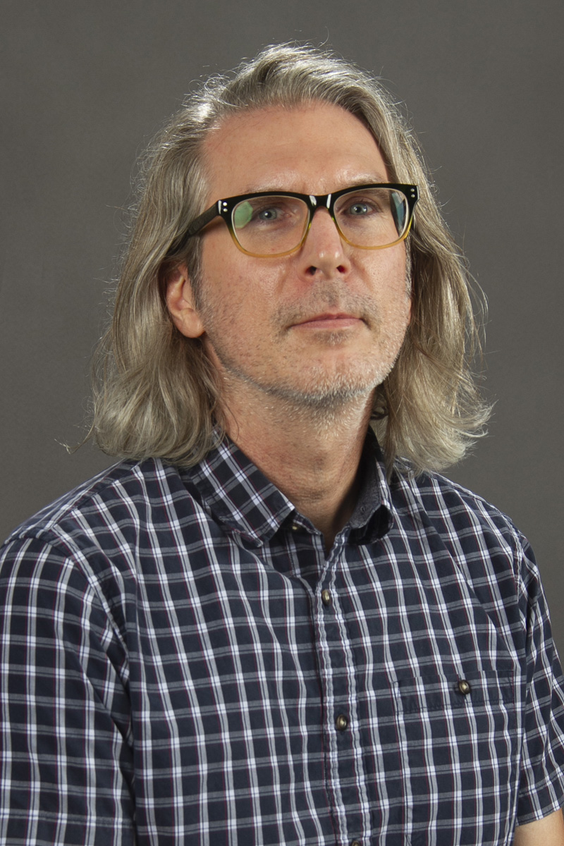man with long gray hair and glasses.