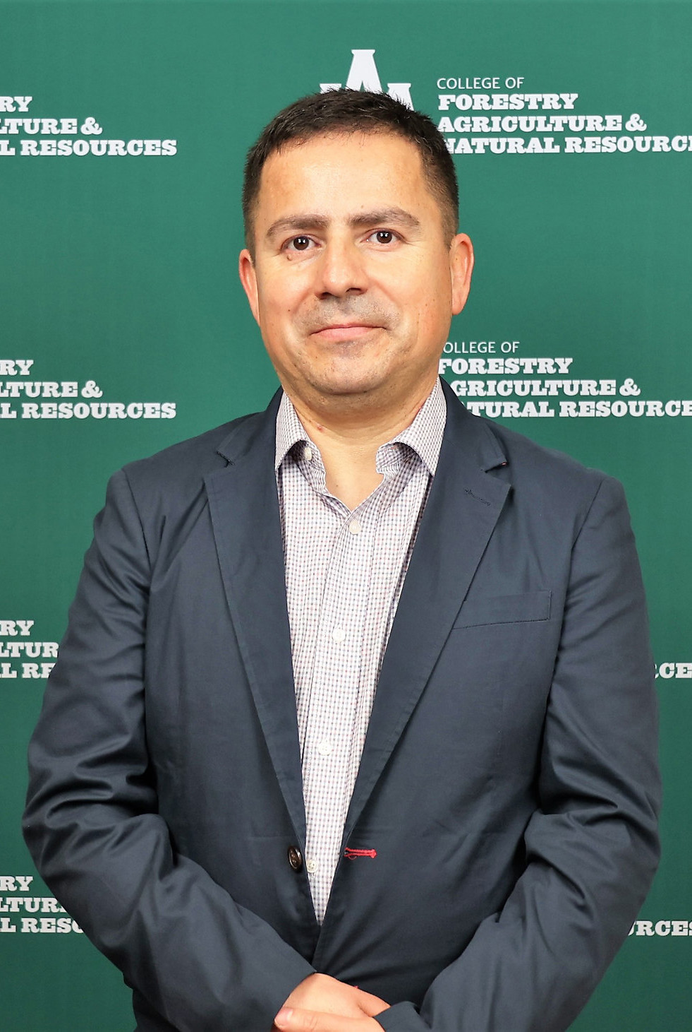 Man with close cropped hair standing in front of green logo background for UA Monticello