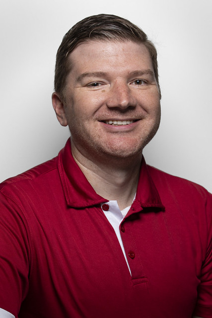 Man smiling, wearing red polo shirt 